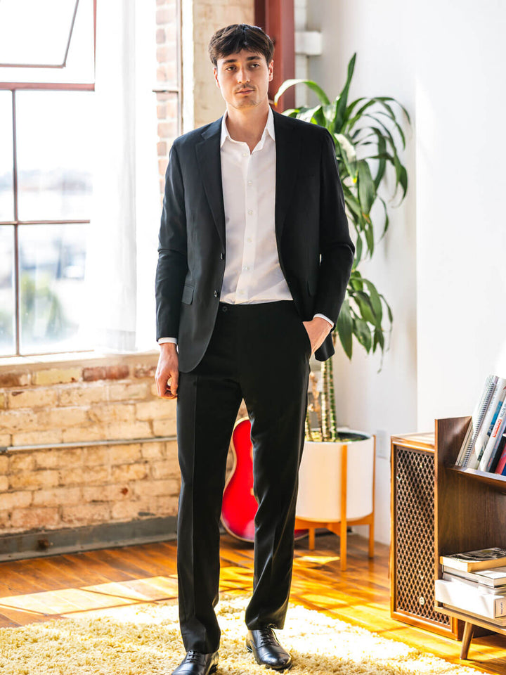 Man poses in Anatoly & Sons deep black suit made from Drago fabric