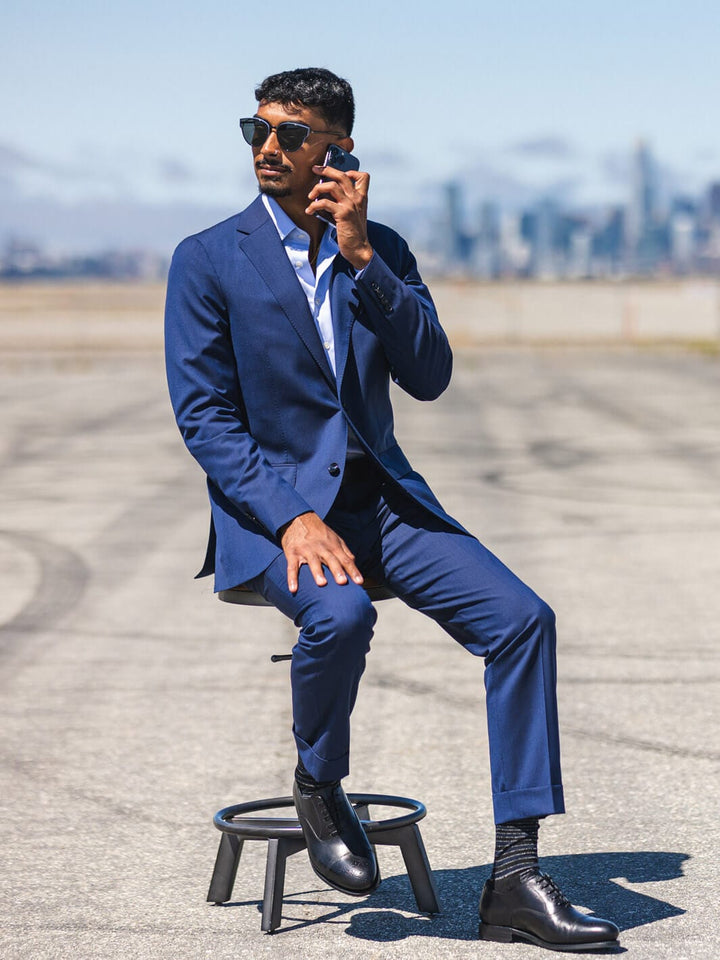 Man sitting on stool in parking lot with shades on wearing Anatoly & Sons Blue Drago Skyfall Suit