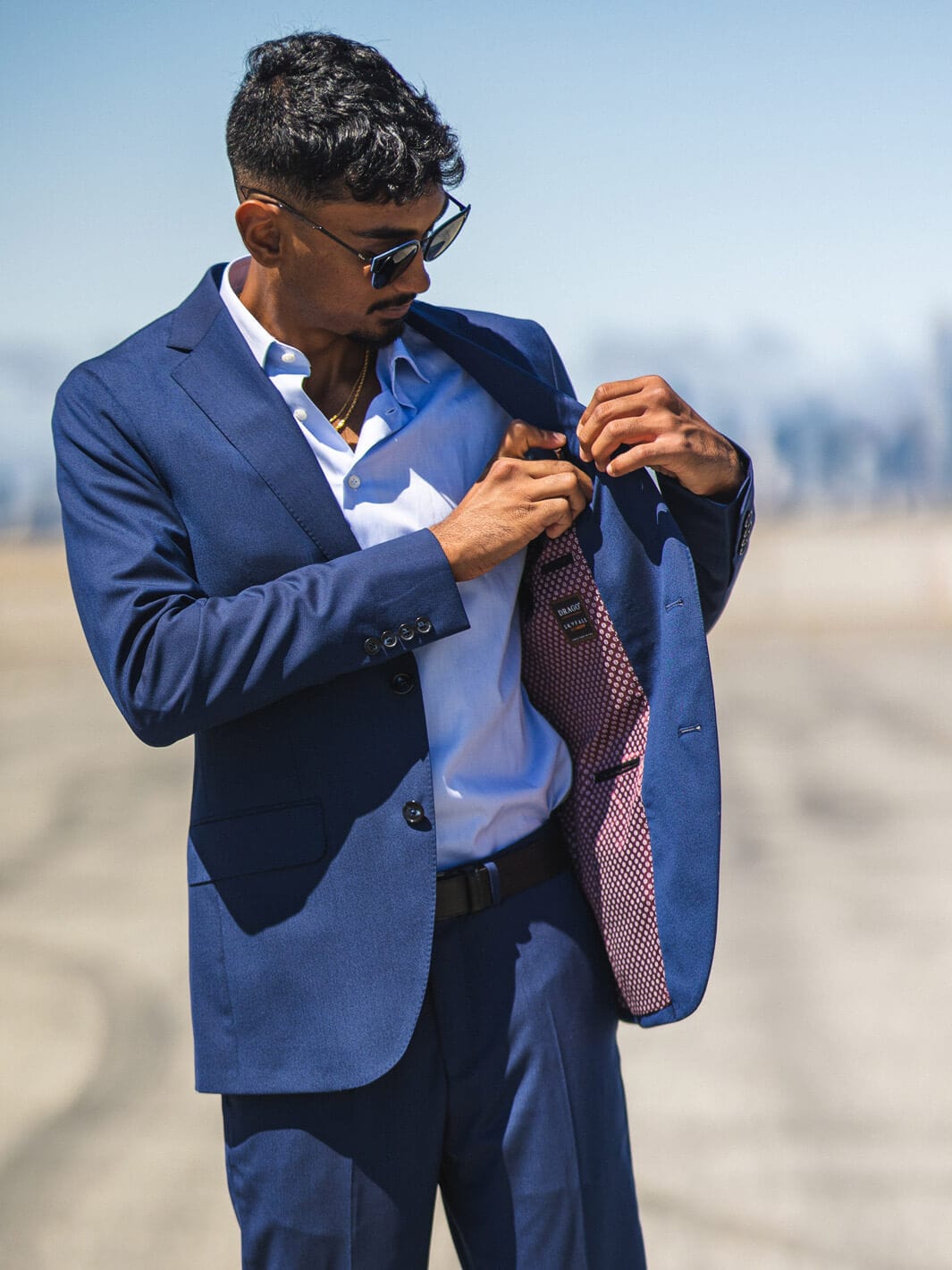 Man in shades putting his phone in inside pocket of Anatoly & Sons Blue Drago Skyfall Suit