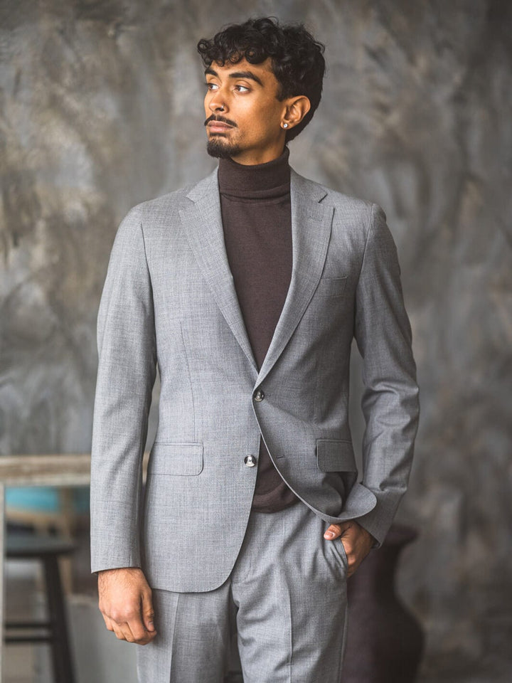 Man posing in Anatoly & Sons Light Grey Drago Skyfall Suit with turtleneck sweater underneath